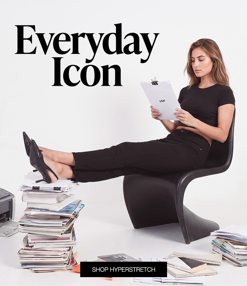 A woman in a black short-sleeve top and black pants sits in a black sculptural chair, reading a clipboard surrounded by stacks of papers. Large text reads 'Everyday Icon' and a banner at the bottom says 'SHOP HYPERSTRETCH'.