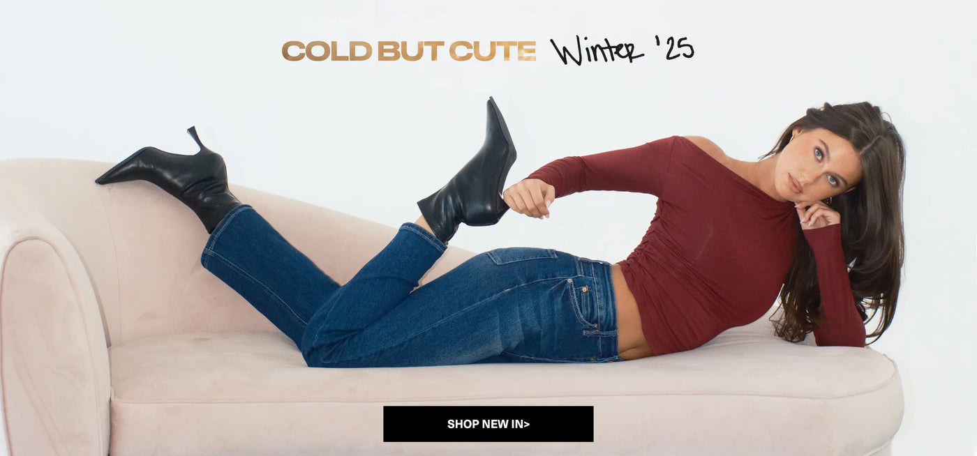 Woman lying on a couch wearing a red sweater and blue jeans with text 'Cold But Cute Winter '25' and 'Shop New In'.