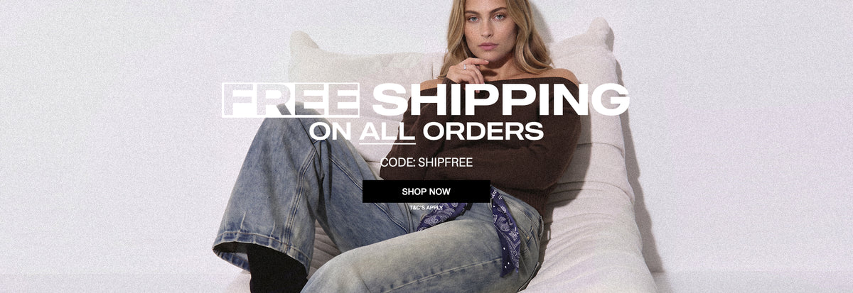 A woman reclining on a white sofa wearing a dark brown top and light blue jeans, with large overlaid text reading 'FREE SHIPPING ON ALL ORDERS' and a 'SHOP NOW' button.
