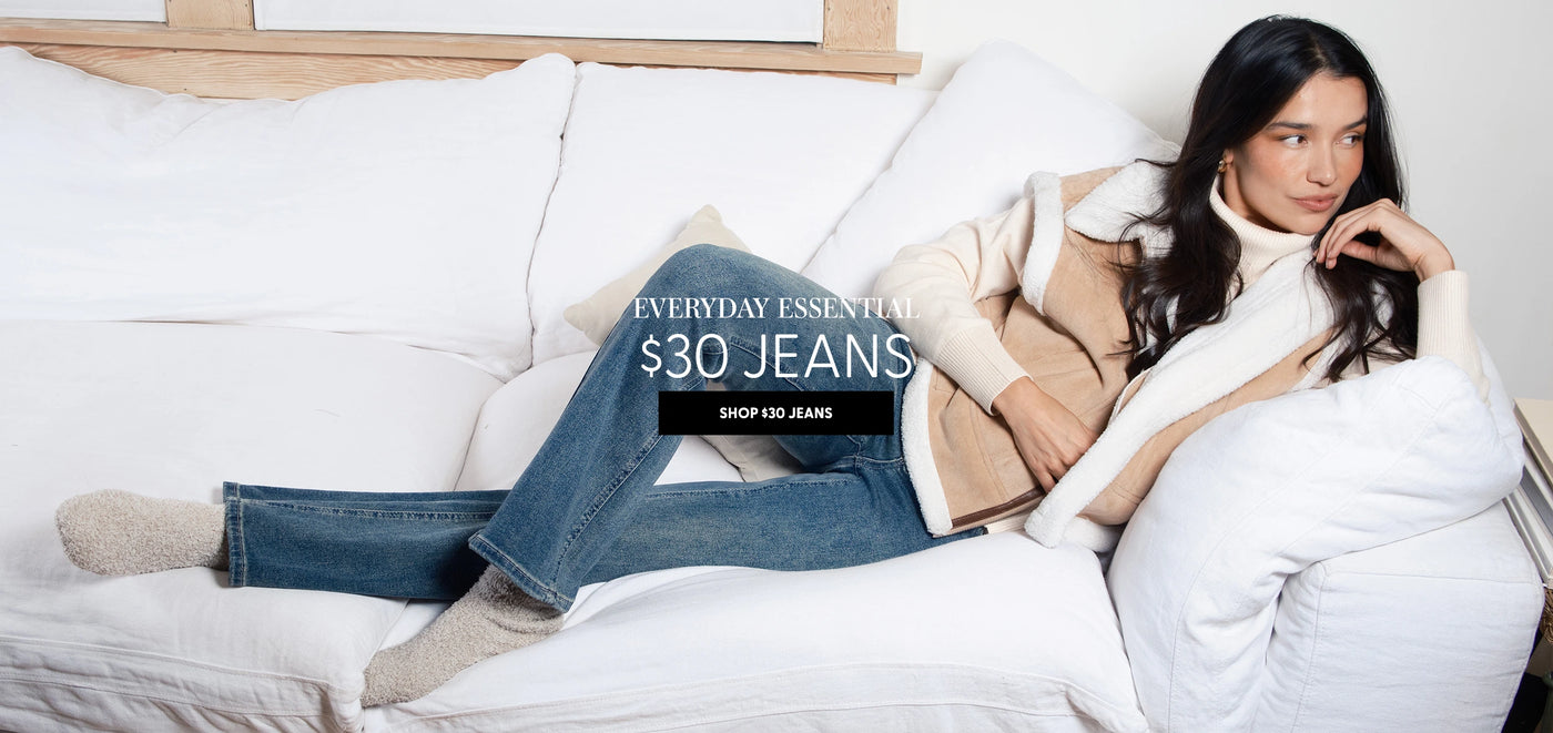 Woman sitting on a couch wearing jeans and a jacket with promotional text overlay.