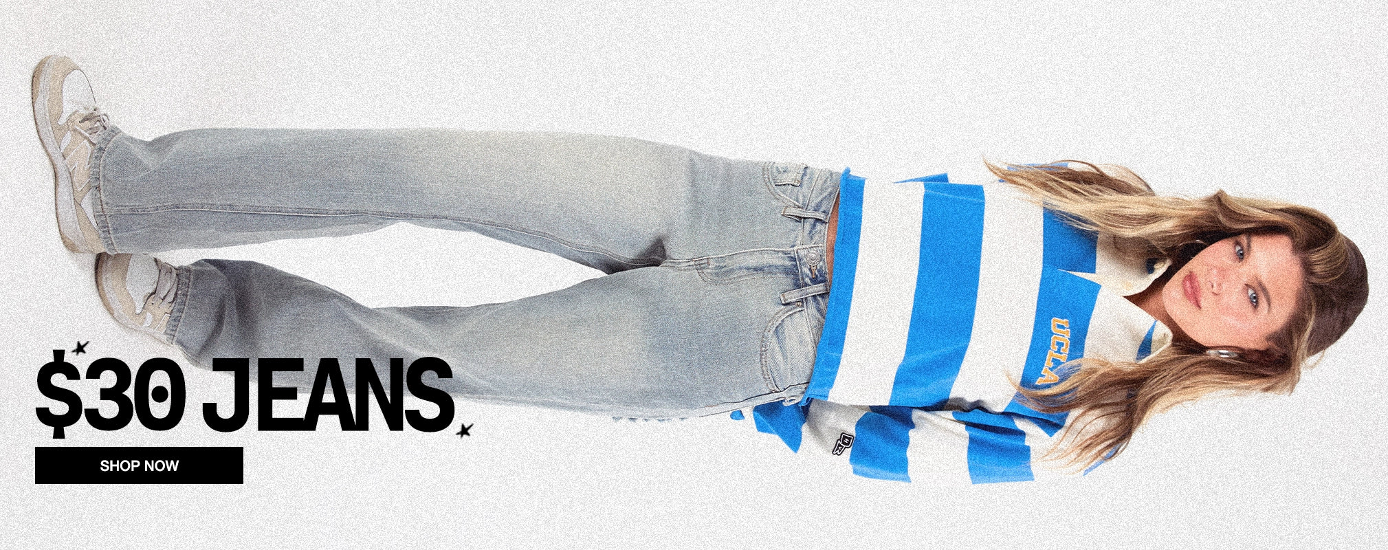 A woman lying on her side wearing light-wash blue jeans and a blue-and-white striped long-sleeve shirt, with text reading '$30 JEANS' and a 'SHOP NOW' button on a white background.